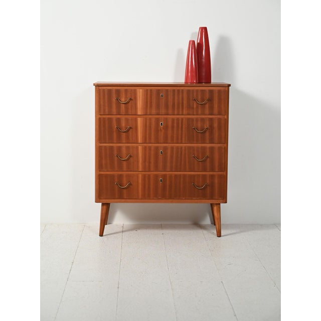 Nordic mahogany chest of drawers with understated lines, slender legs, and classic brass handles. Scandinavian chest of...