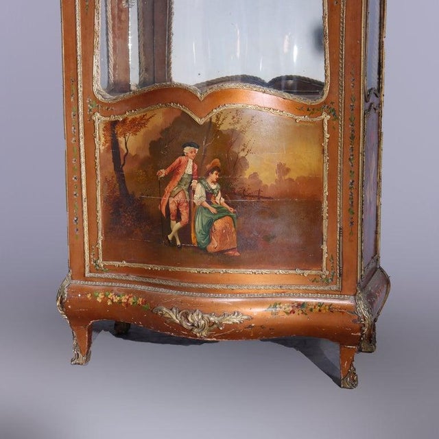An antique French Louis XIV style vitrine offers Vernis Martin decorated case with shaped crest having central cast...
