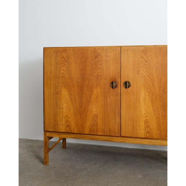 A rare danish mid century wooden "232" cabinet / sideboard in stained oak with and pair of iconic and decorative brass...