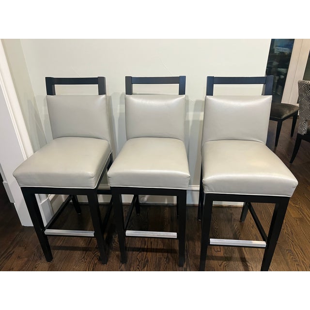 Set of five transitional or contemporary swivel bar stools featuring light gray leather upholstery paired with sleek black...