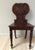 Antique hall chair with dramatic and intricate carving. Solid seat and back with double c-scroll details and fleur-de-lis...