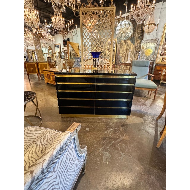 The Jean Claude Mahey Style Black Lacquered and Brass Dresser is a luxurious and elegant piece of furniture perfect for...