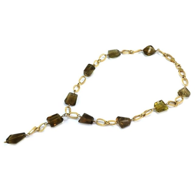 This beautiful vintage lariat necklace is crafted from 14k yellow gold and features double oval textured links accented...