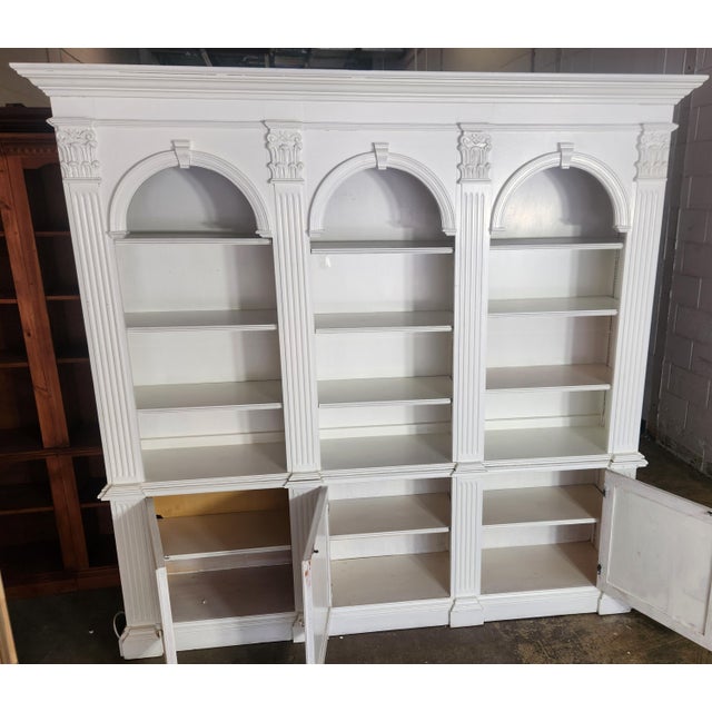 A large two-piece bookcase unit from Pulaski Furniture Co. with a stately neoclassical look. Triple arches, carved wood...