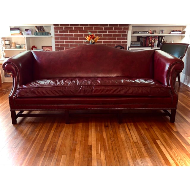 Stately and soulful, this vintage Gunlocke camelback sofa in deep oxblood leather is the kind of piece that anchors a...