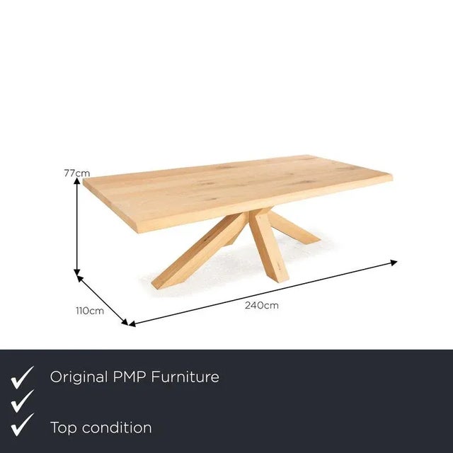 The dining table from PMP Furniture consists of a brown wooden top and stands on a stylish wooden base. It is...
