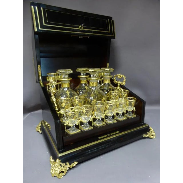 Grande cave à liqueurs en bois noirci époque napoléon iii comprenant un panier amovible muni de trois carafes et douze...