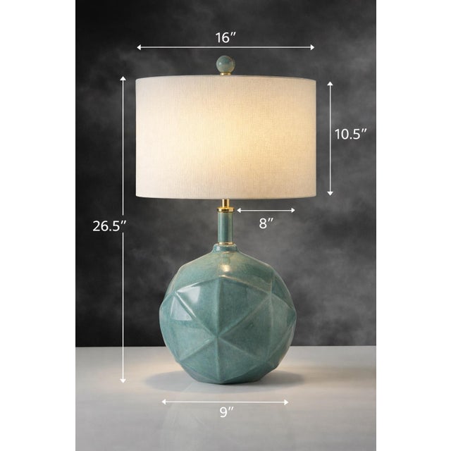 A striking geometric ceramic table lamp finished in a luminous sea-glass teal glaze, accented with polished brass hardware...
