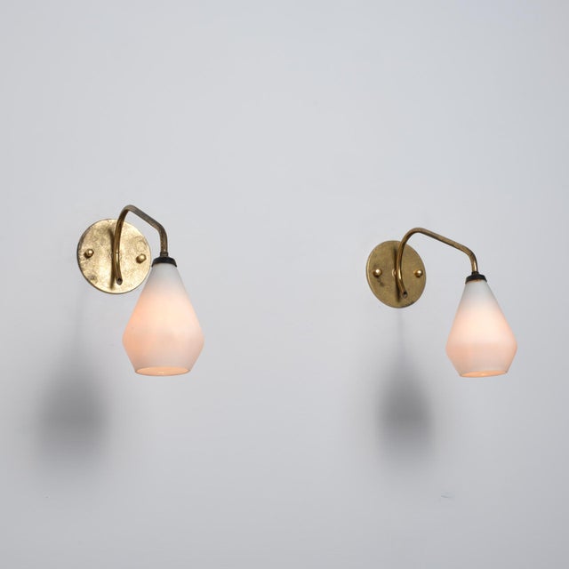 Pair of italian wall sconces from the 1950s, crafted in brass with opaline glass diffusers. The design is simple and well...