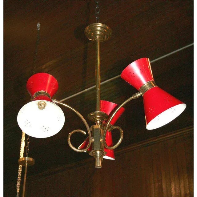 Brass chandelier with three red painted metal conical shades.