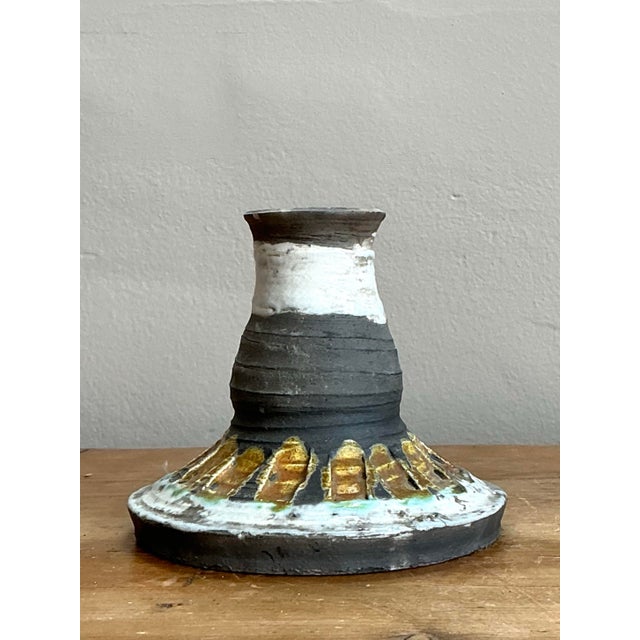This evocative studio pottery candlestick is a masterclass in architectural form and tactile texture. Featuring a flared,...