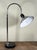 This chrome desk lamp features a swooping fixed curved arm with an adjustable metal shade and a solid black granite base,...