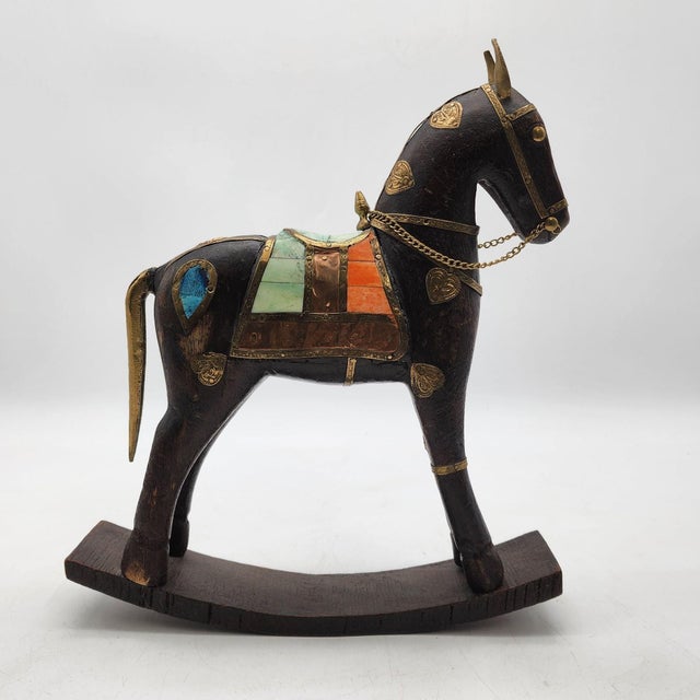 This vintage rocking horse showcases artisanal craftsmanship with a wooden base, intricate brass detailing, and inlaid...