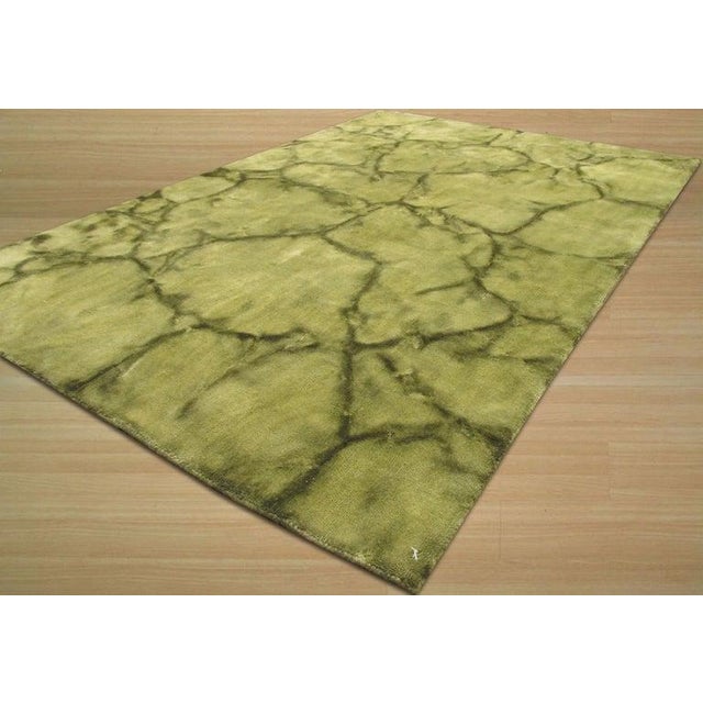 This green wool rug features a hand knotted pile construction and reflects the structural integrity of traditional Oushak...