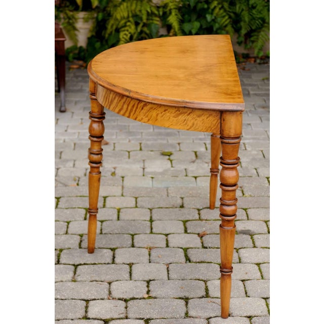 A pair of French Louis-Philippe period maple demilune consoles tables with turned legs from the mid-19th century. Each...