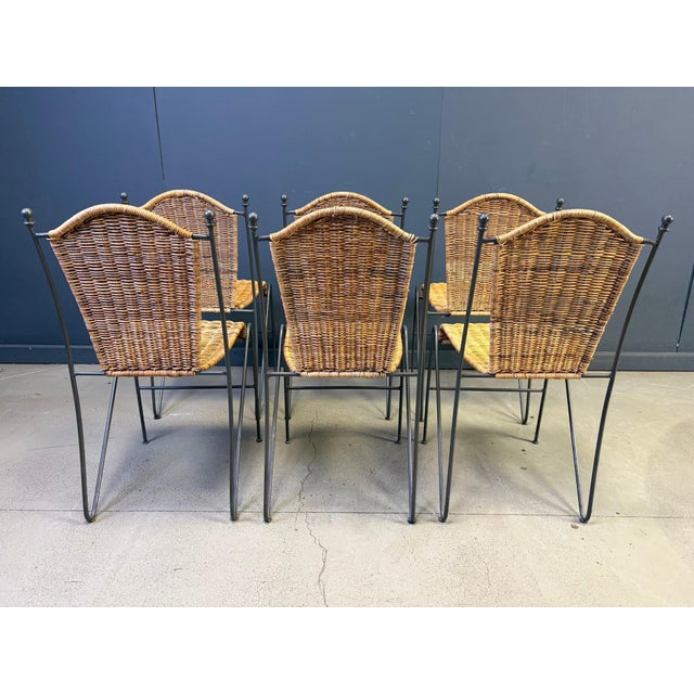 Vintage wrought iron and wicker bistro/dining chairs designed by Frederick Weinberg. Elegant dark grey wrought frame with...