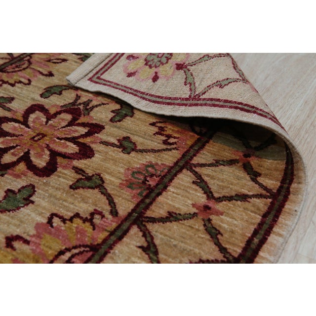 A 3' x 10' hand-knotted wool runner with a beige and gold field with a rust and brown floral lattice, in a low, dense...