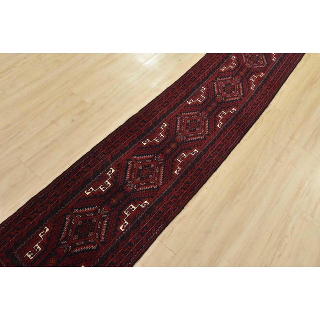 An authentic vintage tribal Baloch runner hand-knotted with fine wool and natural dyes. This nomadic rug features...