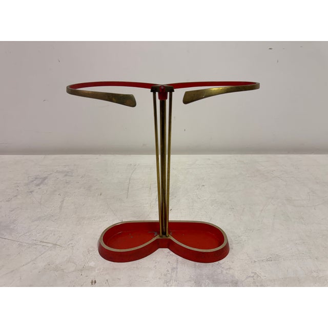 A mid-century umbrella stand in brass and lacquered metal, dating to the 1950s. The design is defined by a light,...