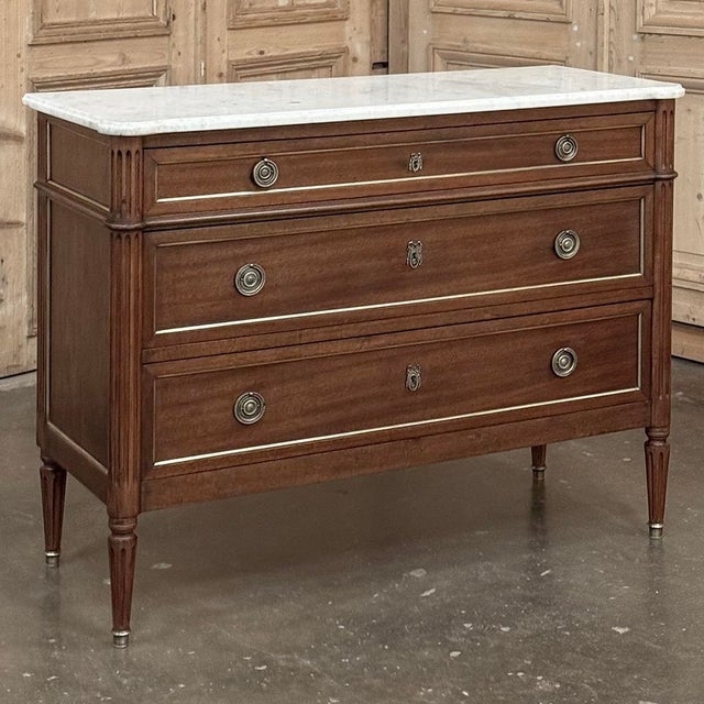 Antique French Louis XVI Mahogany Commode with Carrara Marble combines the stately, tailored elegance with a luxurious...