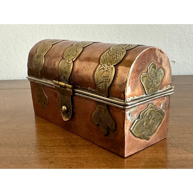 This striking antique betel box features a beautifully aged copper body accented with repoussé brass mounts, forming a...