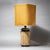 Table lamp featuring a black cylindrical ceramic base decorated with beige rope wrapping. The shade is made of beige woven...