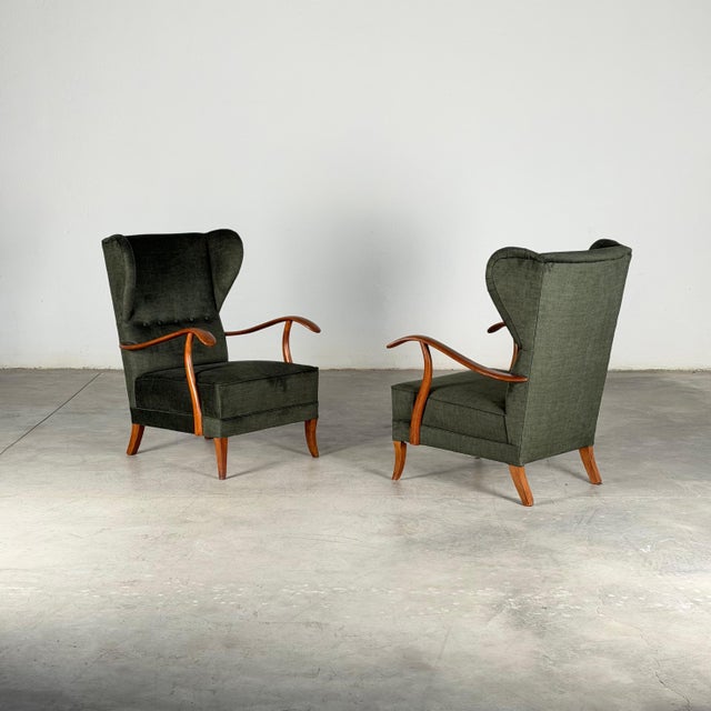 Elegant and sculptural pair of Italian wingback armchairs designed by Melchiorre Bega, dating to the 1950s. These refined...