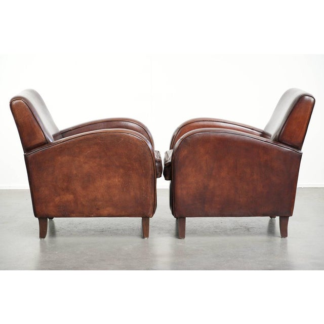 Dark cognac-colored set of 2 sheepskin armchairs with rounded shapes and a sleek design. : This beautiful set of 2 dark...