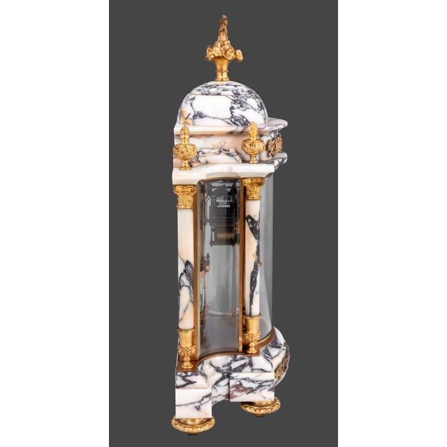 Louis XVI Style Gilt Bronze and Marble Three Piece Clock Set, the clock case with cupola and columnar supports, enameled...