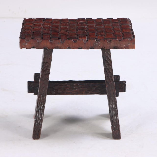 The seat constructed of strap work leather in a basket weave pattern, atop the Brutalist style carved stretcher base.