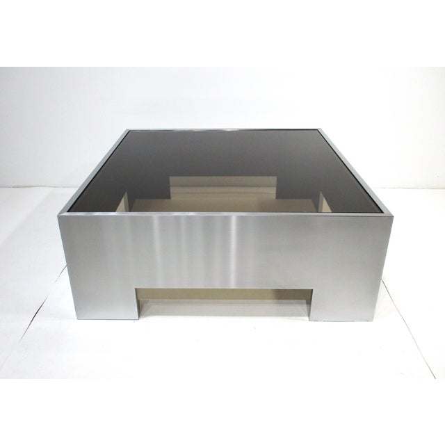 A very well crafted sophisticated stainless steel over wood framed coffee table with smoked plate glass top. A stunning...