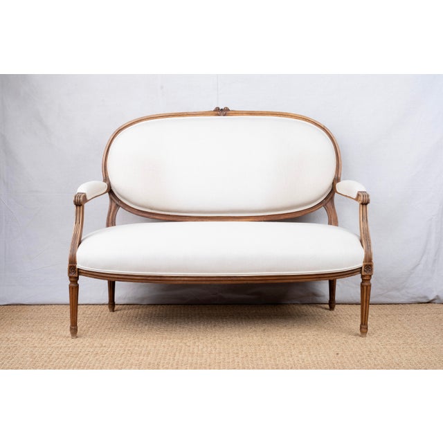 An antique settee, c. 1890, French. Louis XVI style, featuring original carved wood frame with floral motifs and...