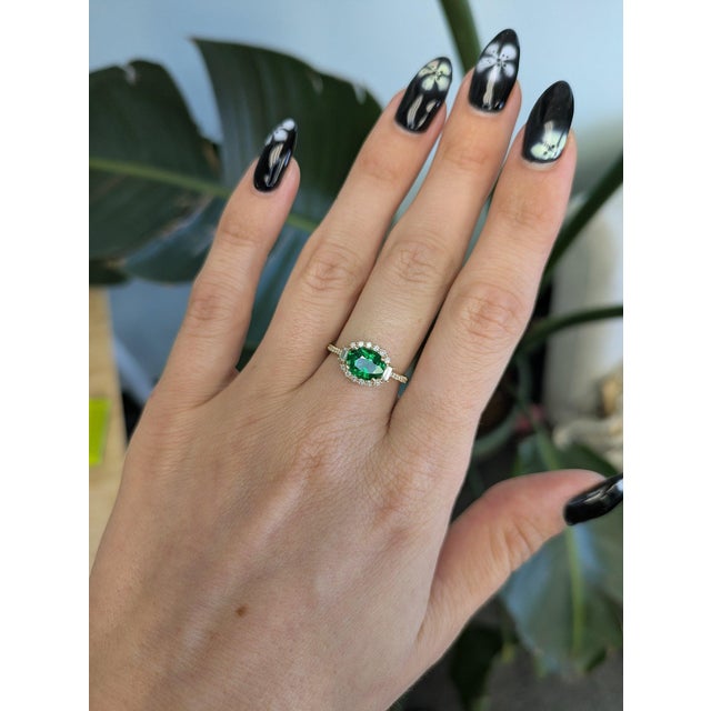 A natural tsavorite garnet from Tanzania glows vivid green at the center of this ring, framed by earth-mined diamonds in...