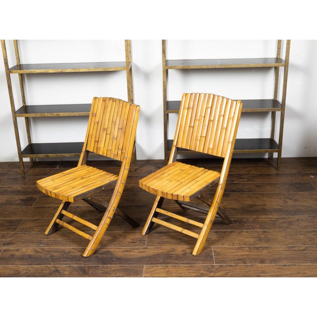 A pair of bamboo folding chairs from the mid 20th century, with light brown patina. Created during the midcentury period,...