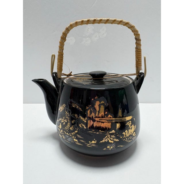 Beautiful vintage Japanese tea set featuring a glossy black glaze with elegant gold scenic landscape design. This set...