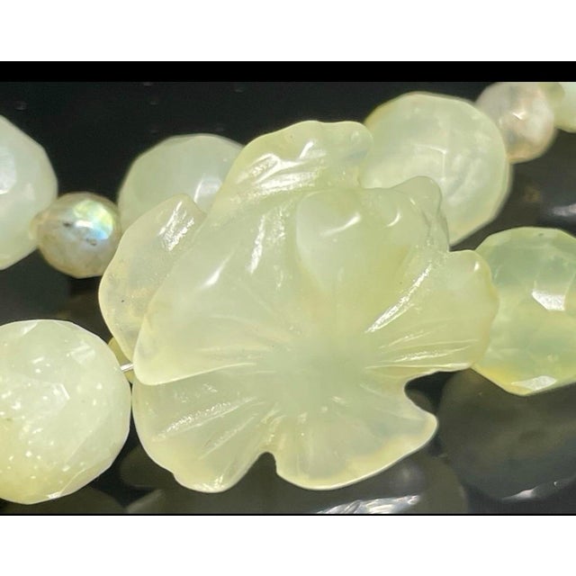 A central hand-carved prehnite floral/flower pendant focal point displaying prehnite's classic translucent pale apple-...