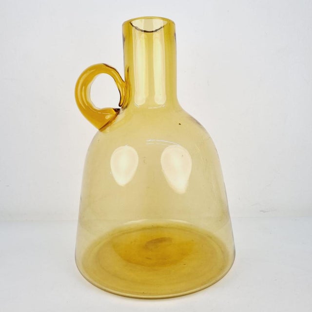 The amber glass, which has a unique shape due to the artisanal blowing technique, was made in the 1920s. A collector's...