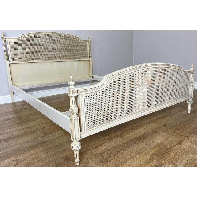 An elegant Vintage French king size bed featuring a soft painted finish, beautifully shaped cane panels to the headboard...