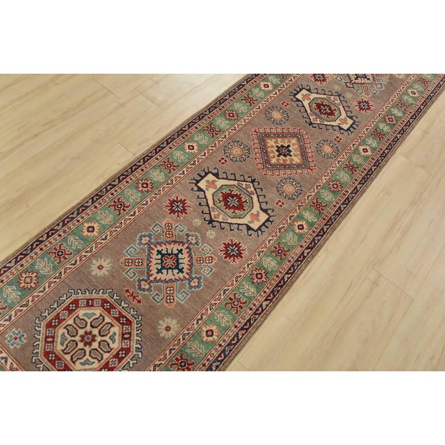 A tribal Caucasian Kazak runner hand-knotted with fine wool on a cotton foundation. This rug features a row of geometric...