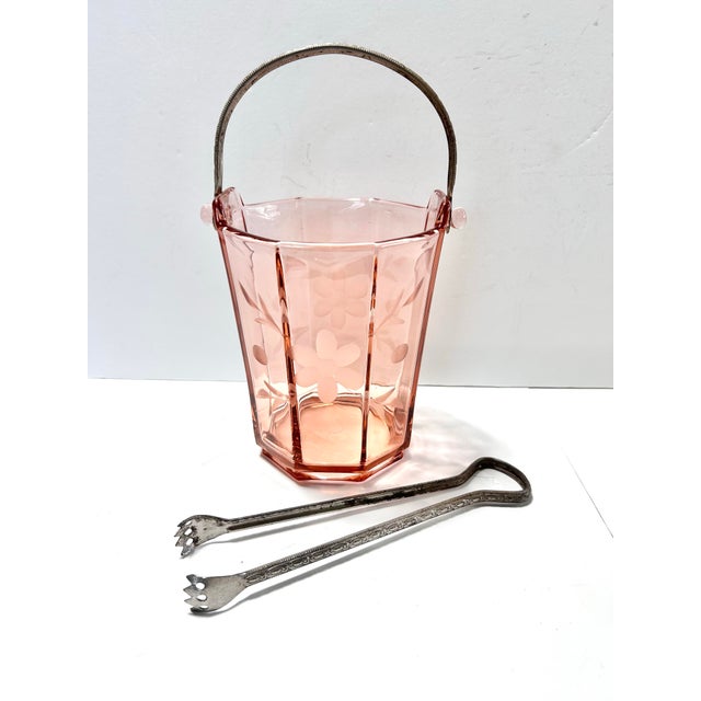 A beautiful vintage pink Depression glass ice bucket featuring delicate floral etching and an elegant handled form....