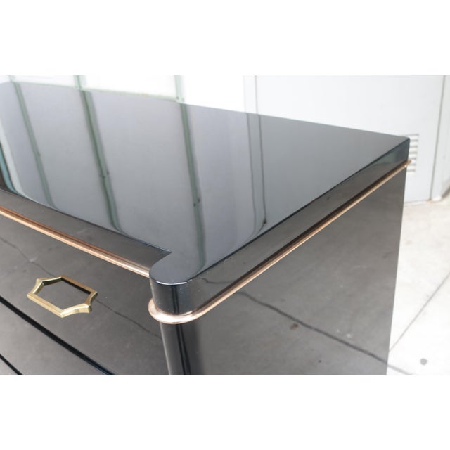 A pair of Art Deco ebonized three drawer chests. Designed by De Coene Frères. Black lacquer with polished brass details,...