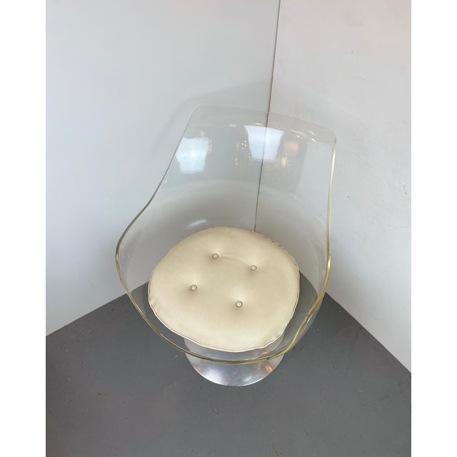 Iconic chair with arms made of a rotating transparent acrylic glass shell with beige leather cushion, mounted on a cast...