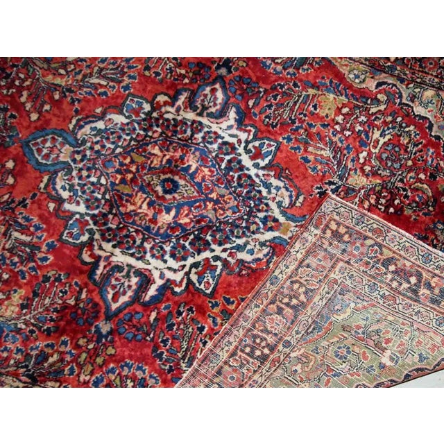 Handmade antique Sarouk rug in red colour. The rug is from the beginning of 20th century in original good condition....