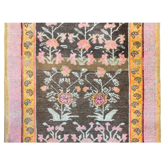 A charming and whimsical early 20th century Central Asian Khotan Rug with an all-over pink peony pattern with two larger...