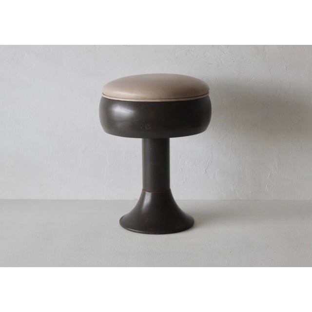 Vintage Space Age tulip-style pedestal stool with a dark flared base, an integrated rounded body, and a swiveling...