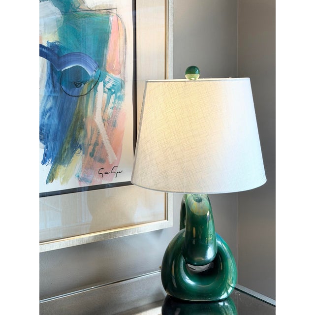 Sculptural ceramic lamp with a fluid, looping form. Rich emerald green glaze with tonal variation. Midcentury modern in...