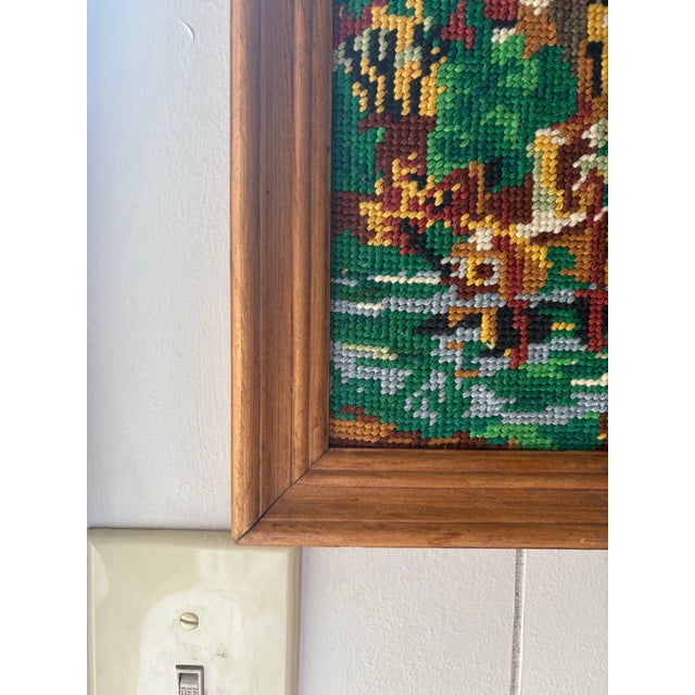 Vintage framed needlepoint landscape featuring a cozy cabin by the water surrounded by autumn trees. This beautifully...