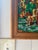 Vintage framed needlepoint landscape featuring a cozy cabin by the water surrounded by autumn trees. This beautifully...
