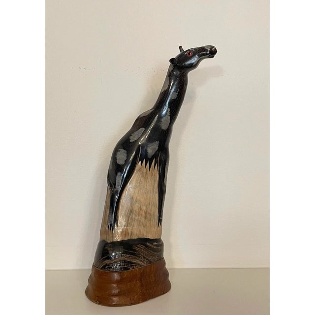 The solid wood giraffe is carved from a single piece of wood. Painted in neutral tones of black, various shades of gray...