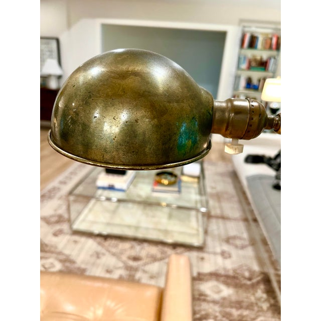 A beautifully aged vintage adjustable floor lamp featuring a sculptural dome shade, warm patinated brass finish, and white...